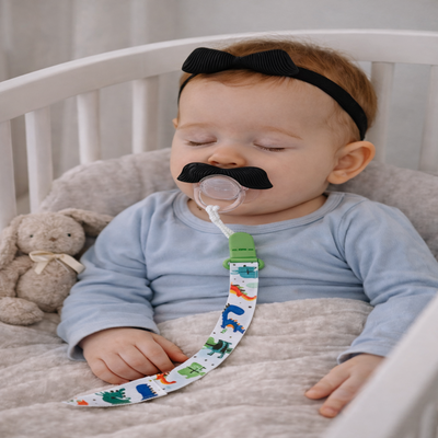 attache sucette moustache vert bébé dans berceau