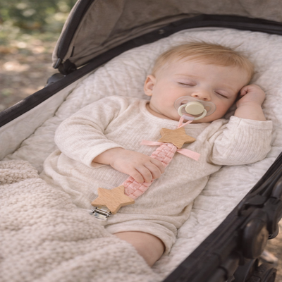 attache tetine bois sécurisée rose clair dans poussette